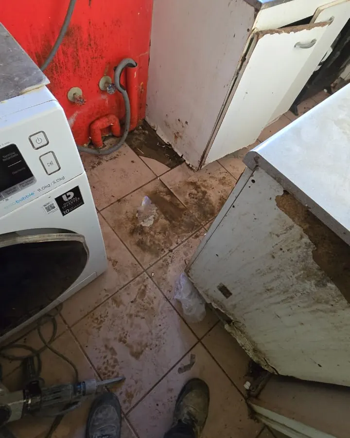 Piso de una logia con agua y barro junto a la lavadora
