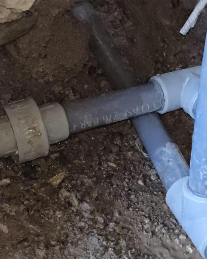 Cañerías grises con una unión nueva dentro de la excavación bajo el piso