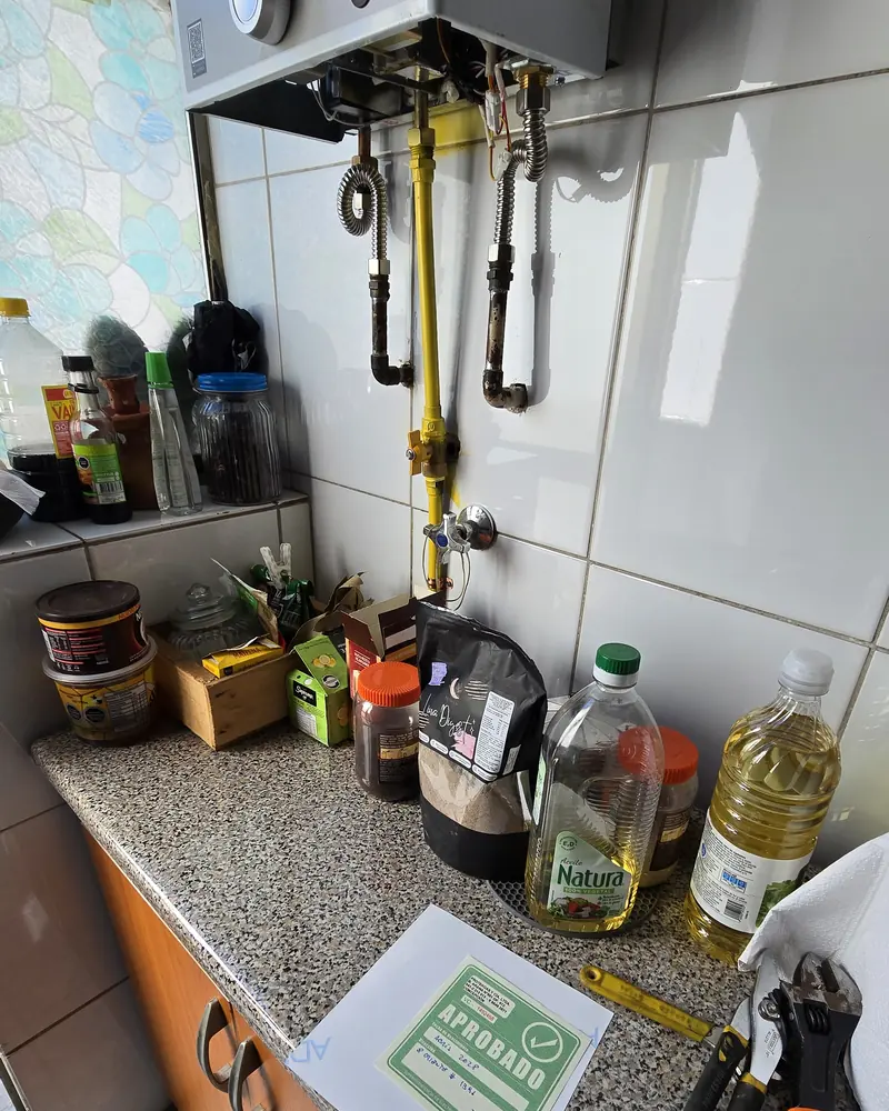 Calefont en la pared de una cocina con cañerías de gas amarillas