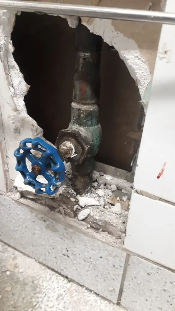 Llave de paso antigua de manilla azul en un muro abierto