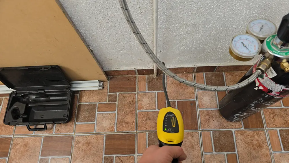 Detector electrónico de gas y cilindro con manómetros sobre el piso de una logia